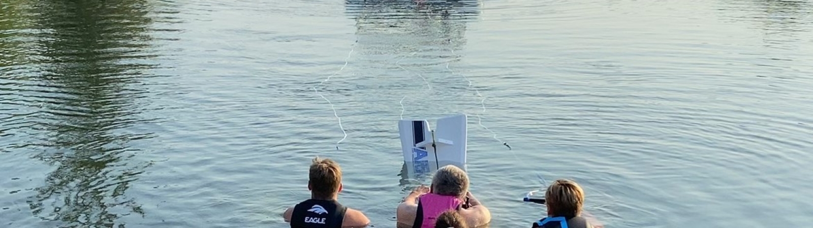3 waterskiers in a lake behind a boat